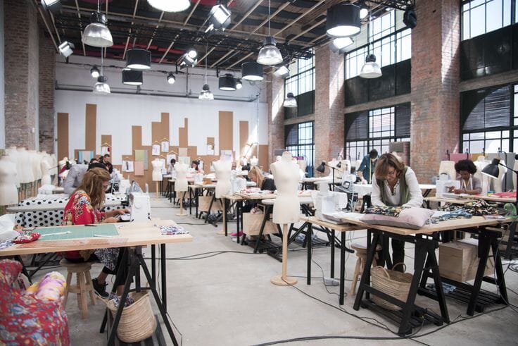 Factory scene with sample garments grouped by style, the kind of pre-production setup a tight capsule of 5-12 pieces enables.
