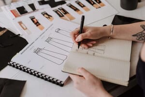 Designer sketching technical flats in a notebook