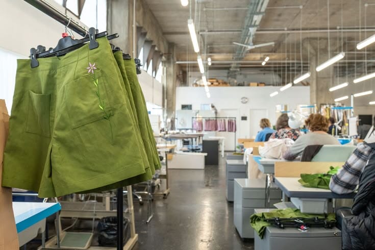 Sampling table with garment toiles and tech-pack notes during a pre-production review session.