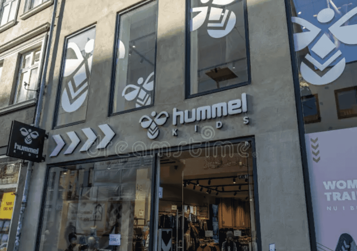 Logo e identidade visual da Hummel, marca dinamarquesa de sportswear fundada em 1923 com €326 milhões em receita 2024, património centenário e reposicionamento streetwear-heritage.