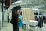 Worker inspecting finished garments hanging on rails