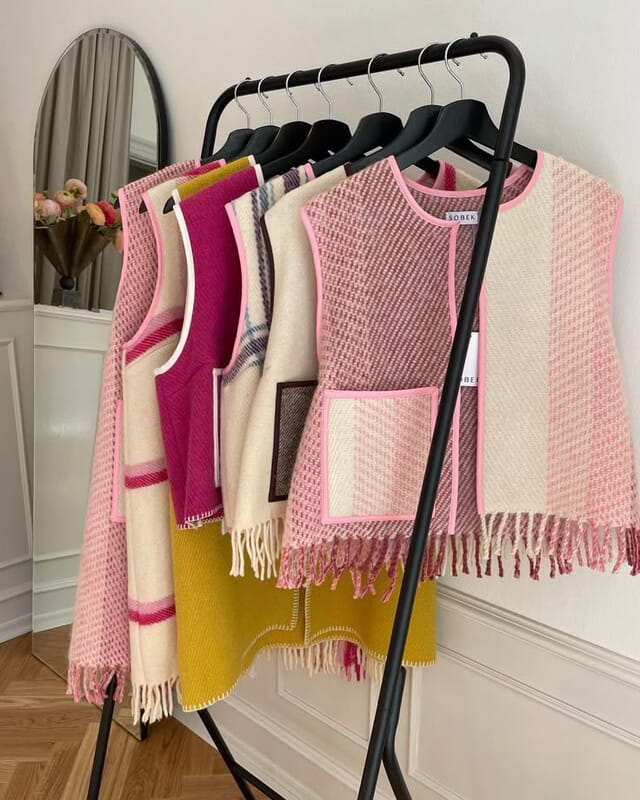 Coletes de malha em tons rosa e amarelo num cabide