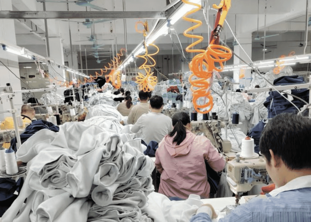 Rows of machinists on a sewing line under overhead air hoses