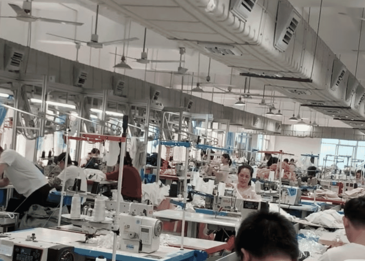Large sewing hall with rows of machinists under ventilation ducts