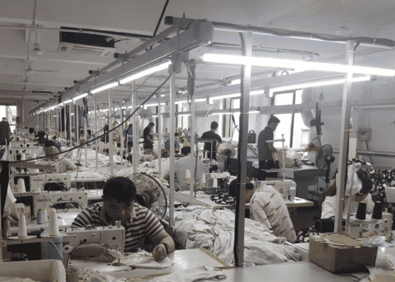 Operator sewing at a lockstitch machine at the front of a long production line