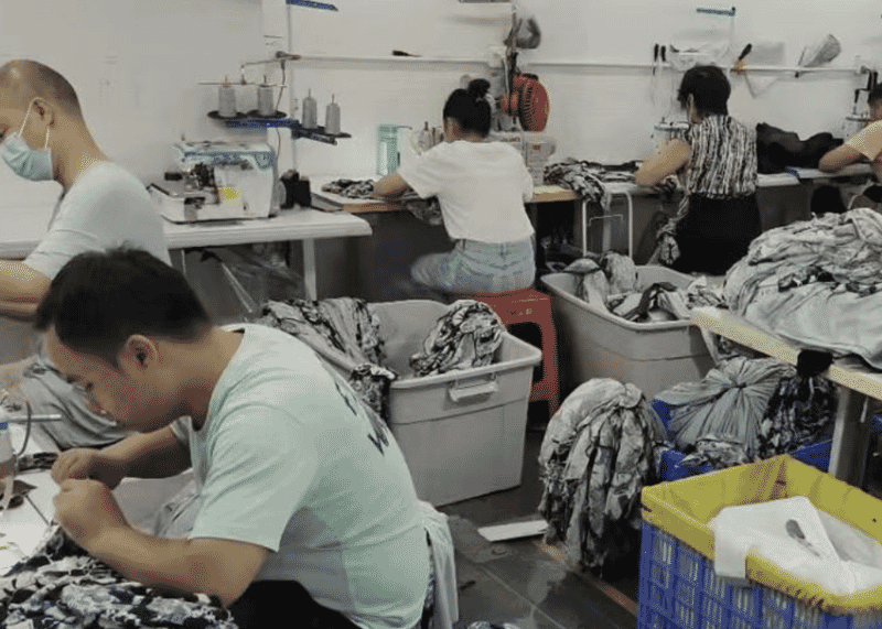 Operators sewing and trimming printed fabric pieces from crates