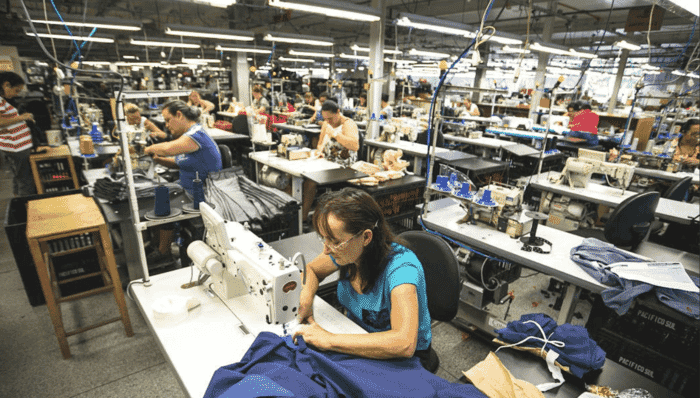Workers operating sewing machines inside a modern Portuguese textile factory with industrial lighting and organised production lines.