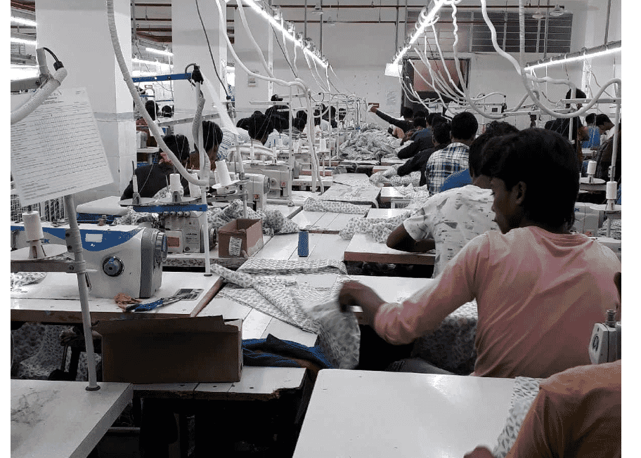 Rows of sewing stations on a large garment factory floor in India