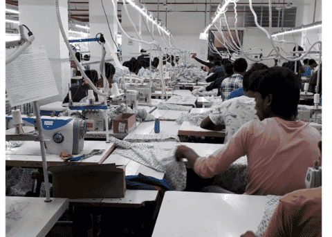 Rows of sewing stations on a large garment factory floor in India