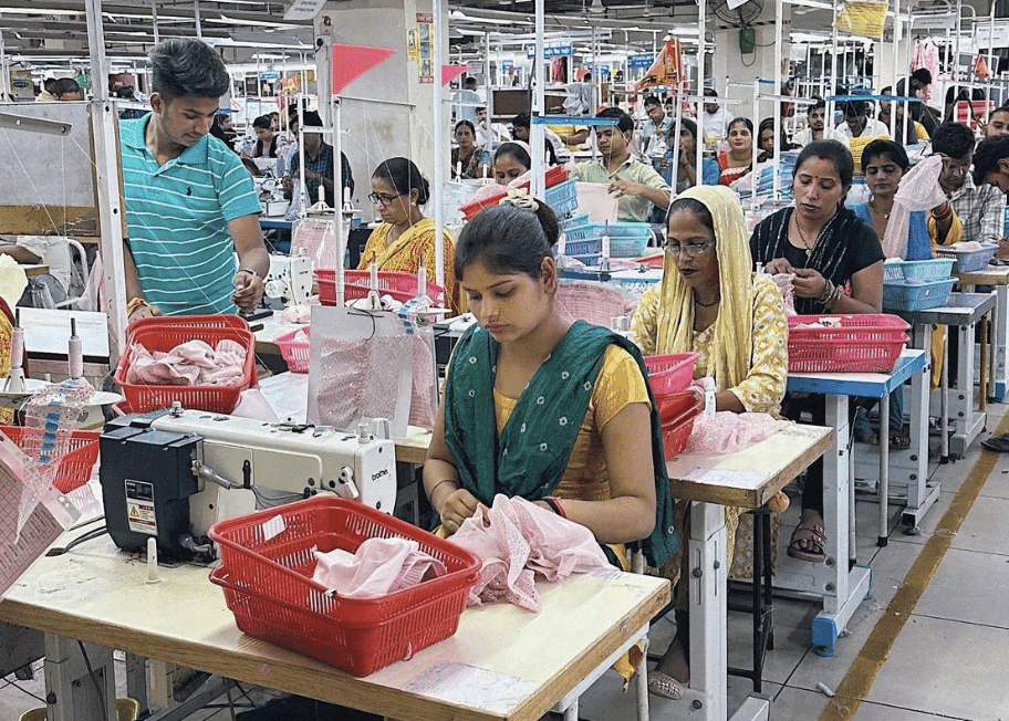 Sewing operators working through bundles of pink garments in red crates