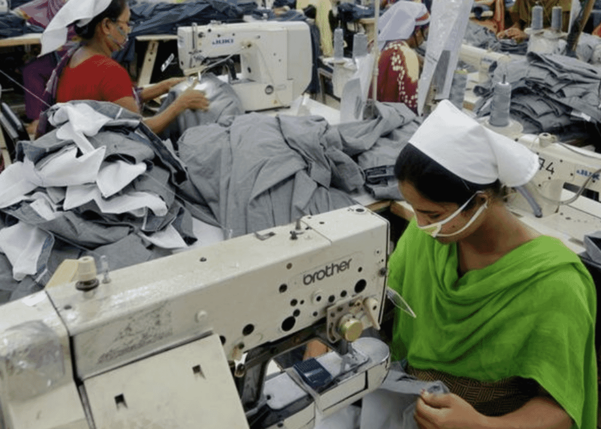 Machinists sewing grey fabric panels on a garment production line