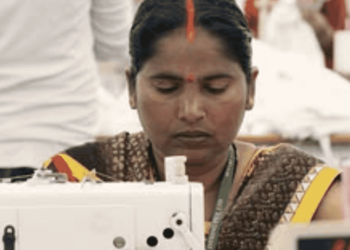 Machinist in a sari sewing at a white sewing machine