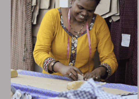 A worker hand finishing woven fabric on a cutting table