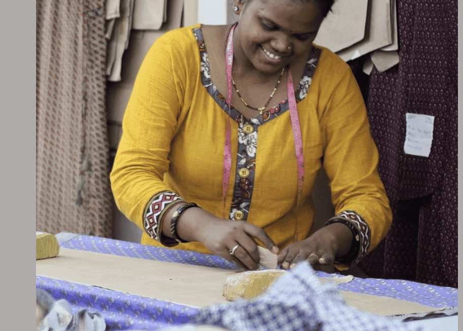 A worker hand finishing woven fabric on a cutting table