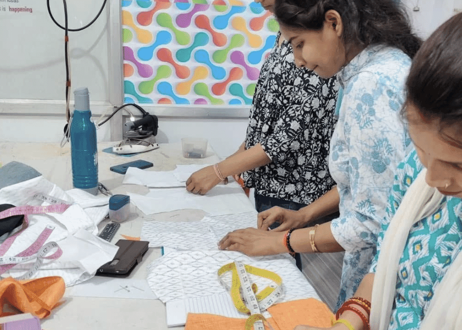 Pattern makers marking and cutting on a sampling table