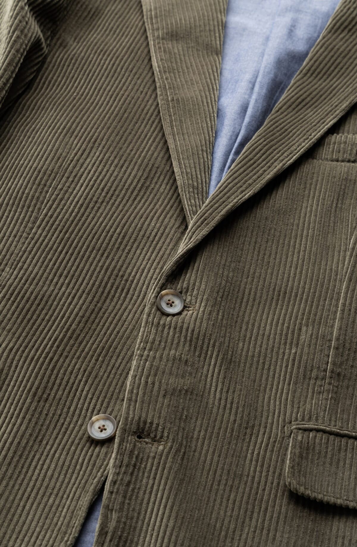 Olive corduroy blazer with a notched lapel and horn buttons, close-up