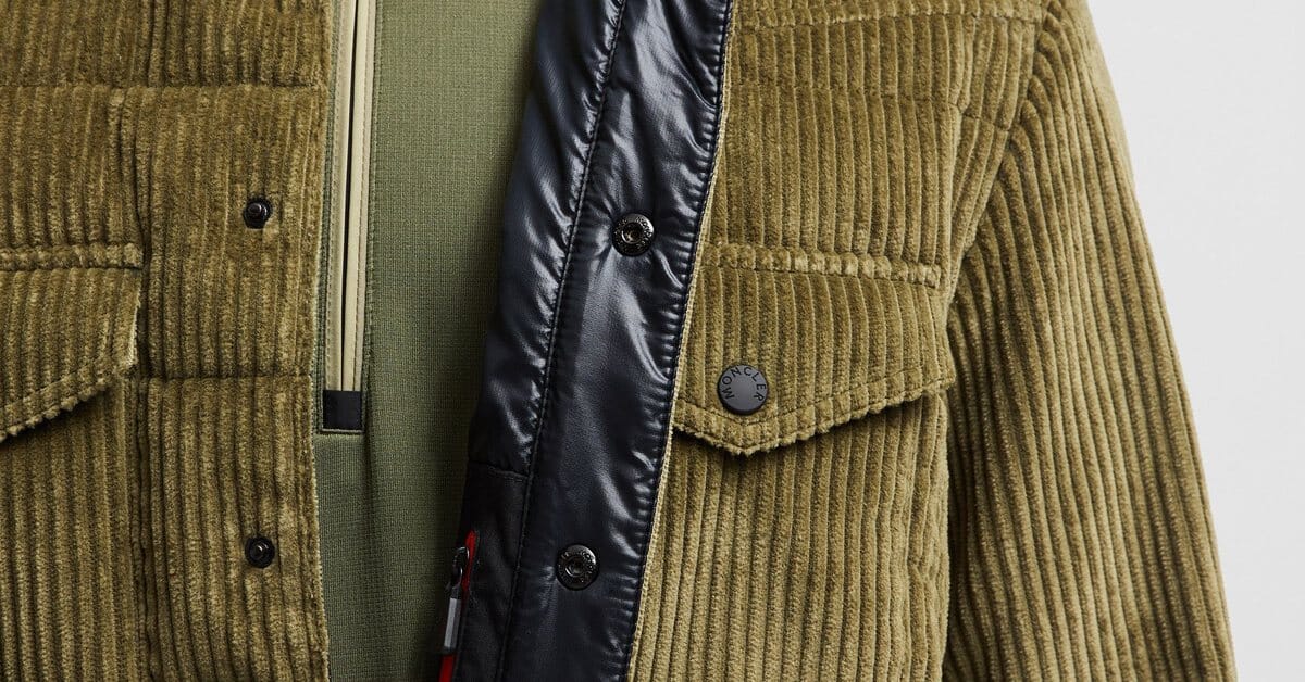 Olive corduroy jacket with a black quilted placket and press studs, close-up