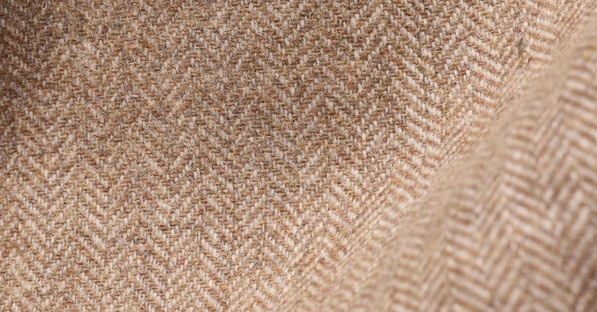 Folds of beige herringbone wool tweed in close-up