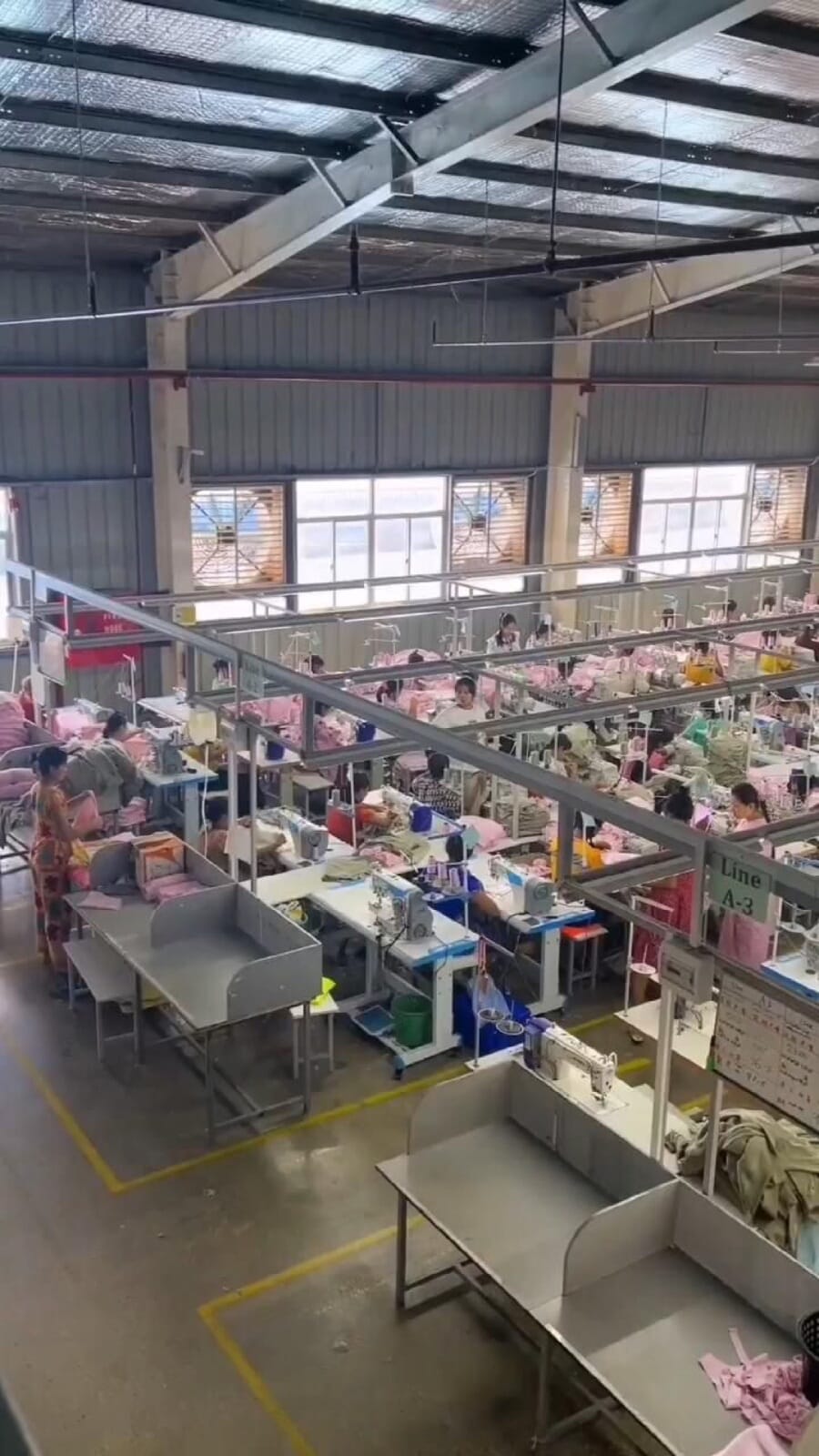 High-ceilinged production floor with sewing stations and steel work tables