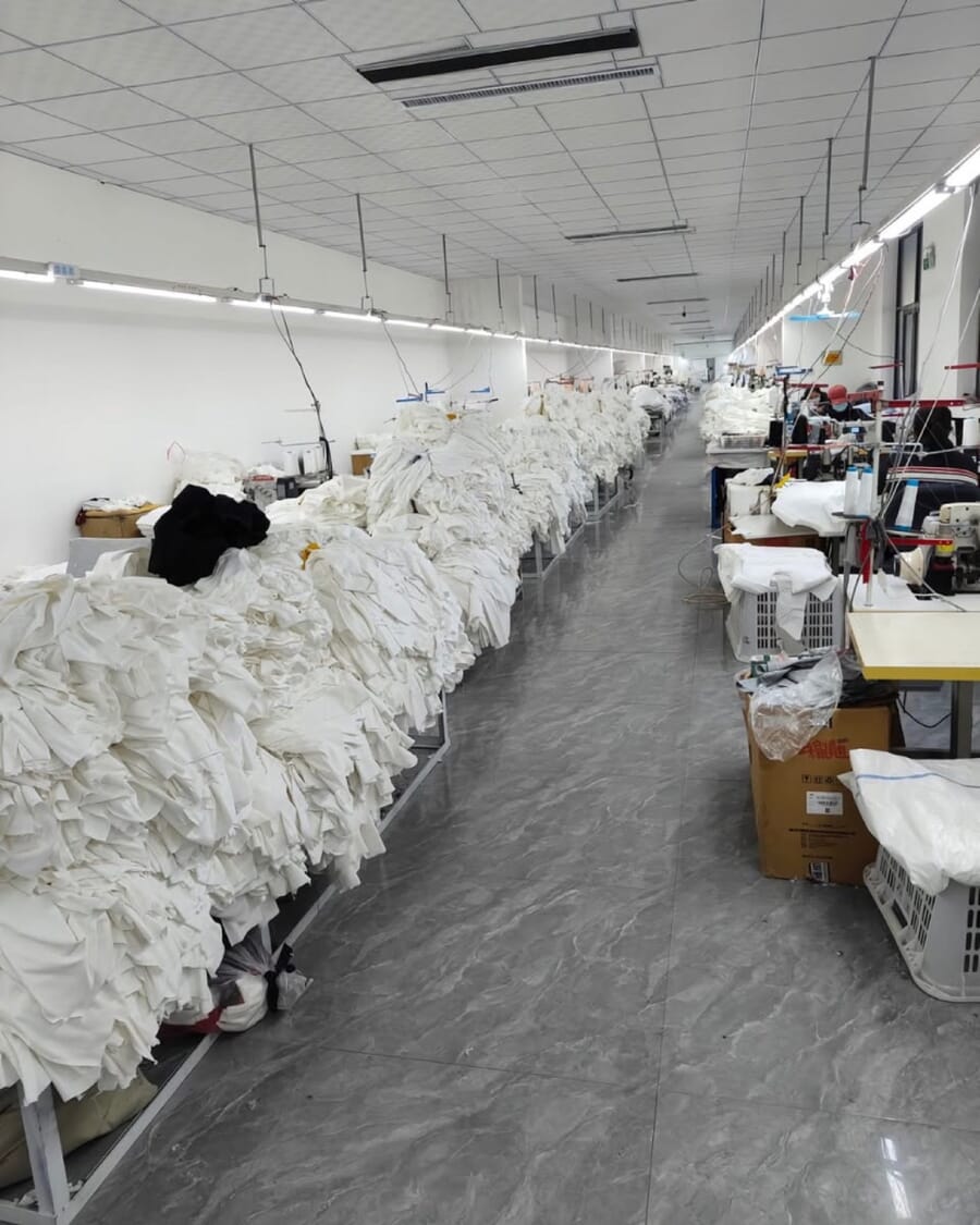Long aisle with tables piled high with white garments waiting for the next step