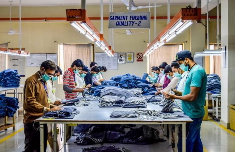 Finishing team checking and folding denim at a long table under a quality sign