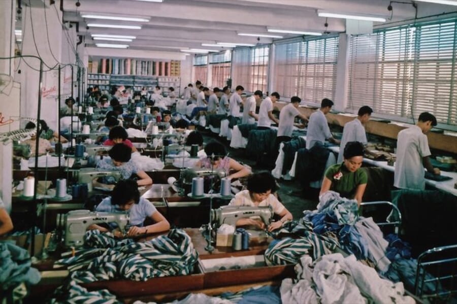 Sewing hall with operators working on striped tops along long rows