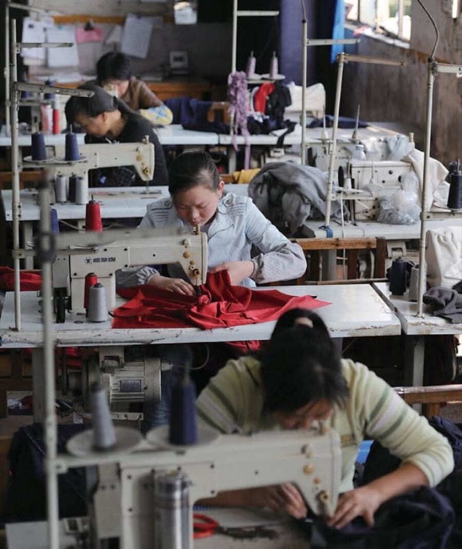 Operators at lockstitch machines sewing red and dark garments