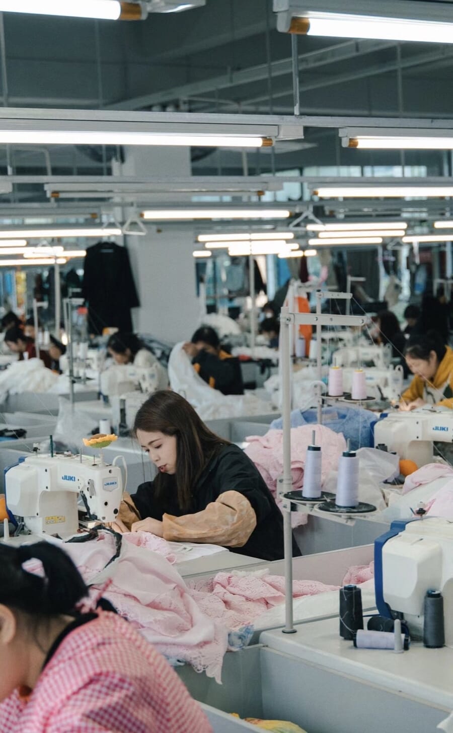 Operator sewing a pink garment in a bright sewing room