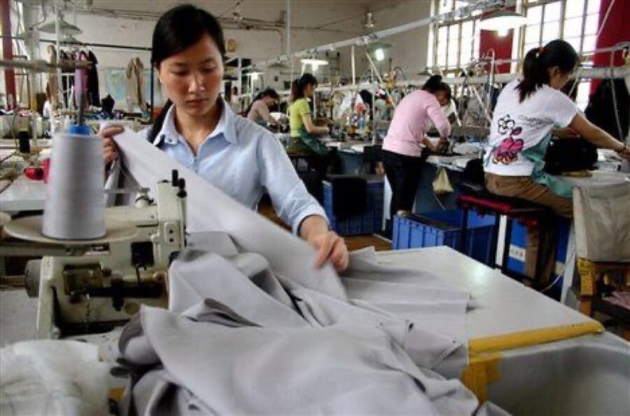 Operator guiding a grey garment through her sewing machine