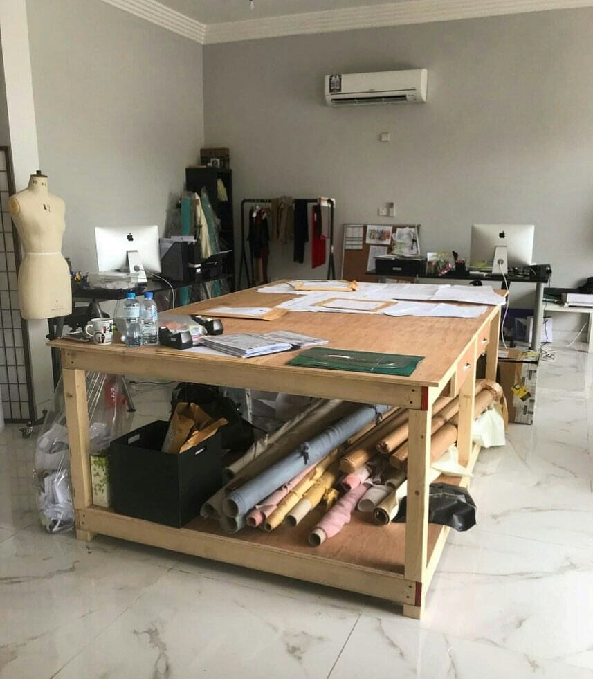 Sample room with a large cutting table, patterns and a dress form