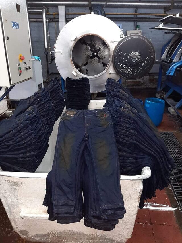 Dark washed jeans piled in a laundry cart after washing