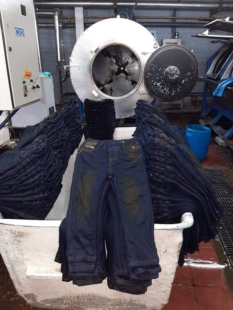 Dark washed jeans piled in a laundry cart after washing