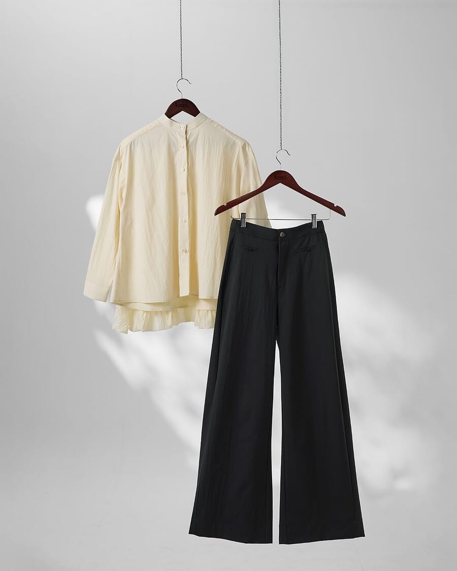 A cream woven shirt and black wide-leg trousers on hangers