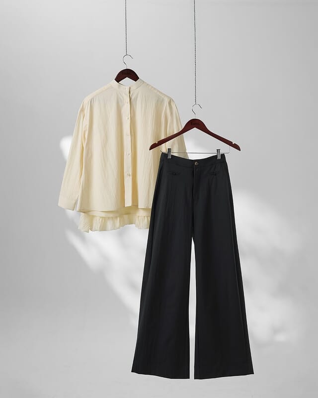 A cream woven shirt and black wide-leg trousers on hangers