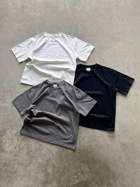 Three short-sleeve cotton tees laid flat in white, grey and navy