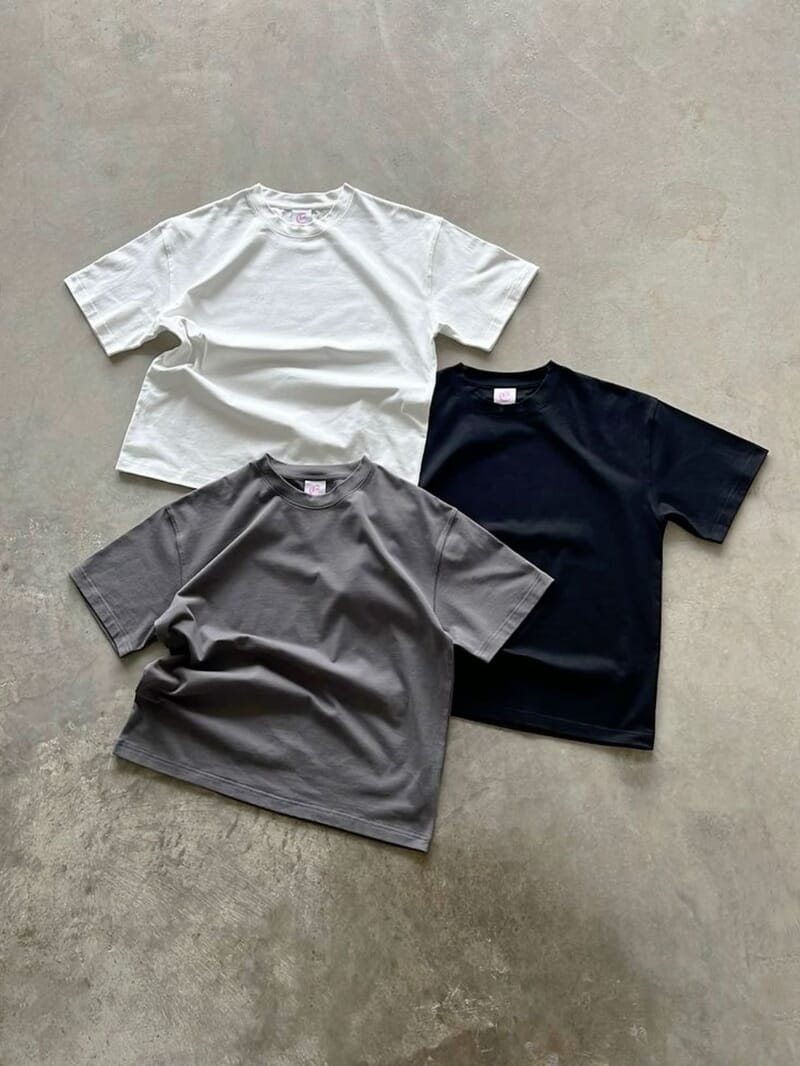 Three short-sleeve cotton tees laid flat in white, grey and navy