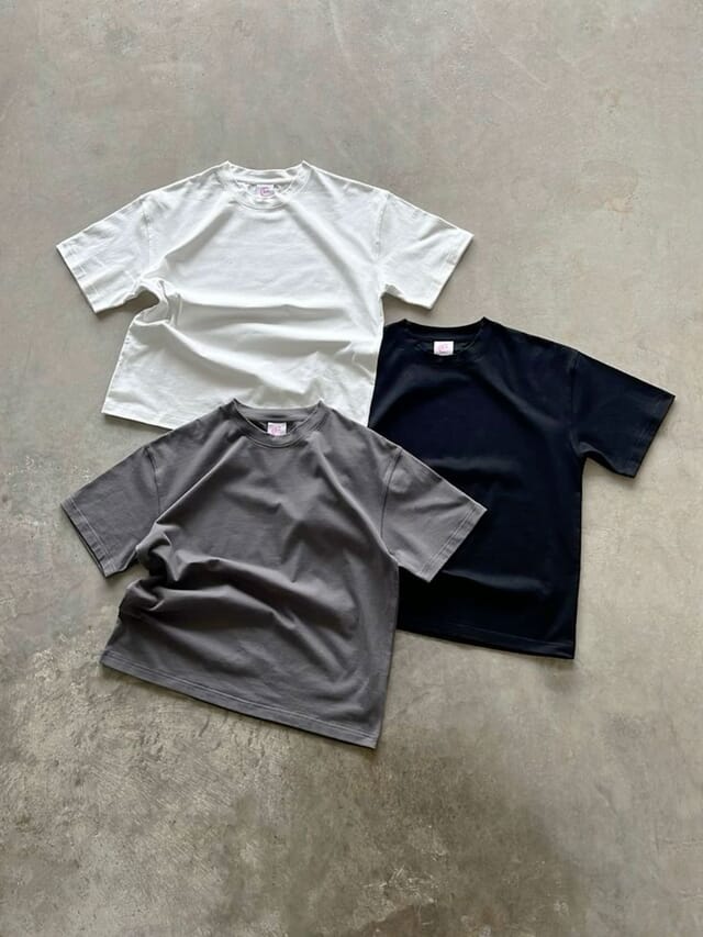 Three short-sleeve cotton tees laid flat in white, grey and navy