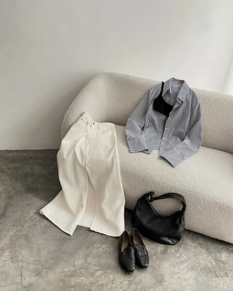 A striped shirt and cream trousers styled on a sofa