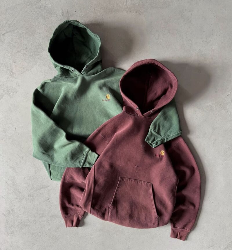Two heavyweight fleece hoodies laid flat, green and burgundy