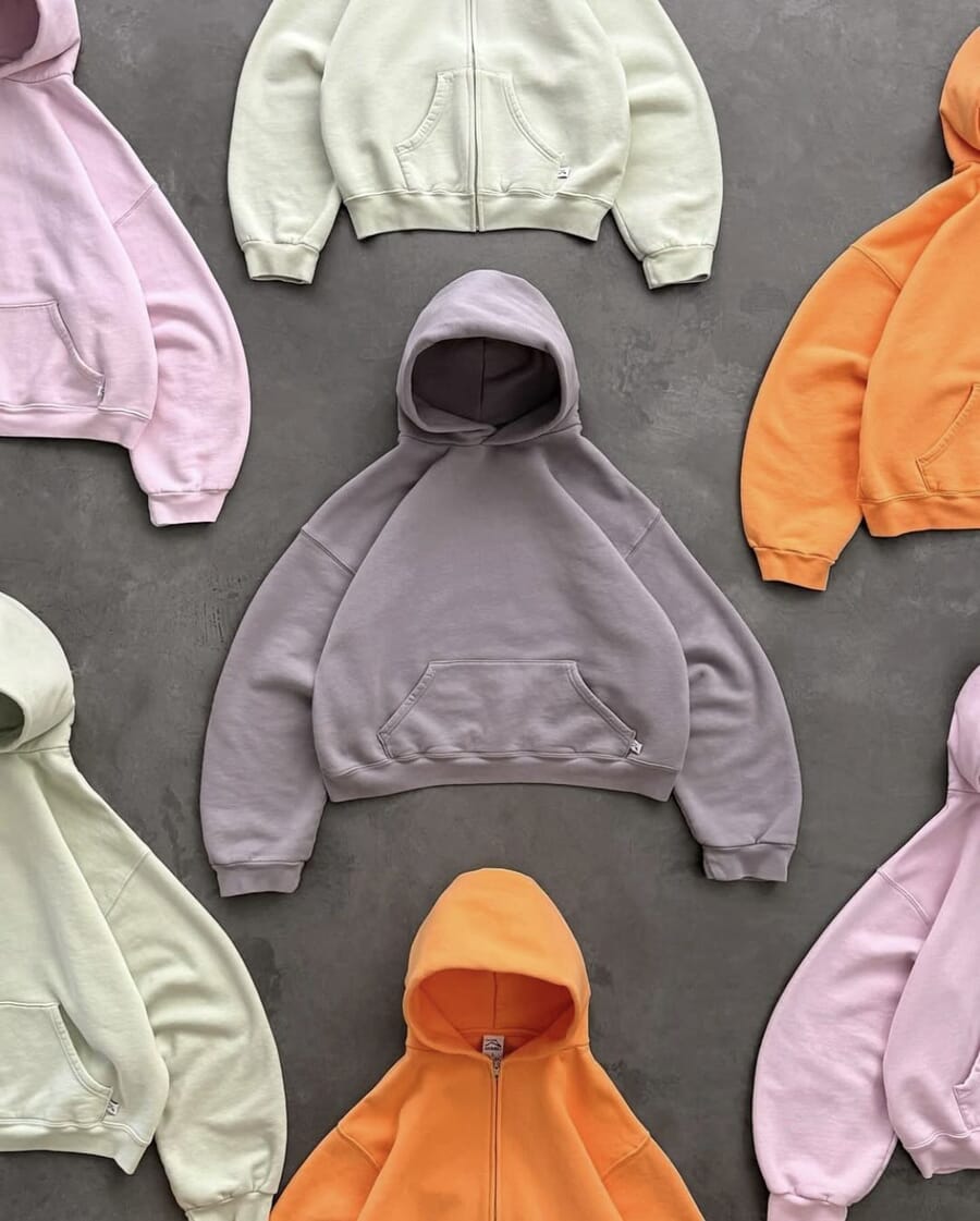Cropped fleece hoodies and zip hoodies laid flat in lilac, pink, orange and mint