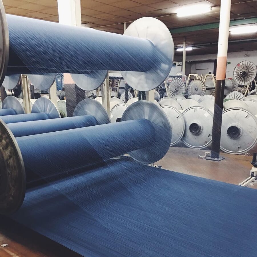 Indigo warp beams on the floor of a denim mill