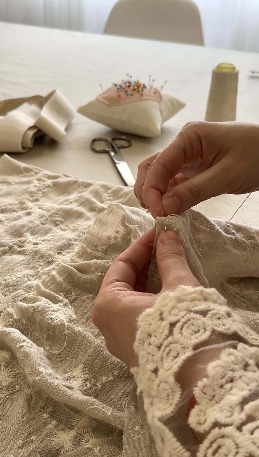 Hands finishing a lace trim on a sample