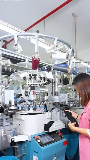 Operator checking a sock knitting machine