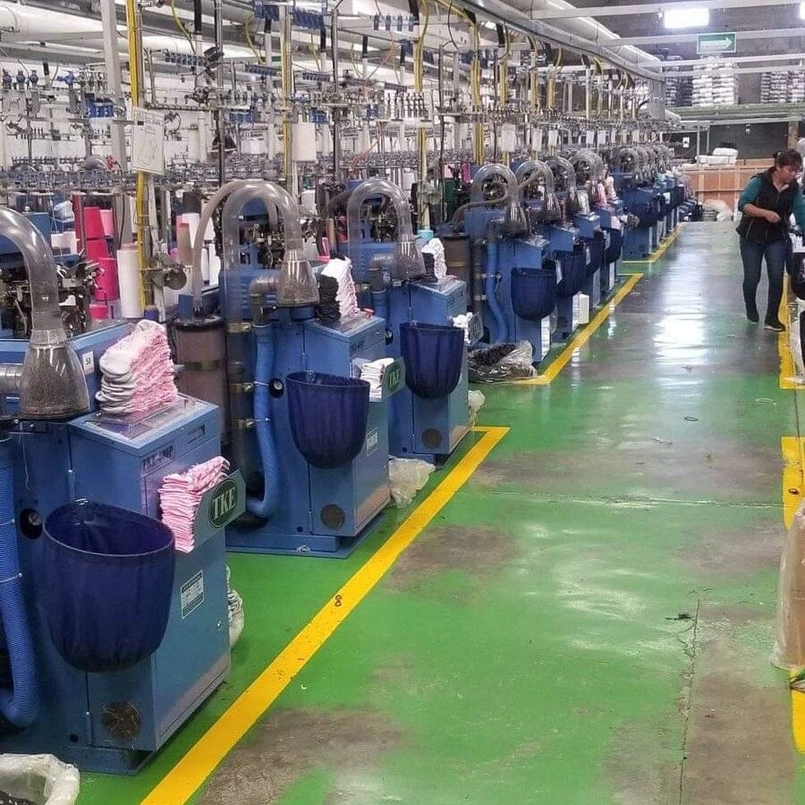 Rows of sock knitting machines with finished socks in the bins