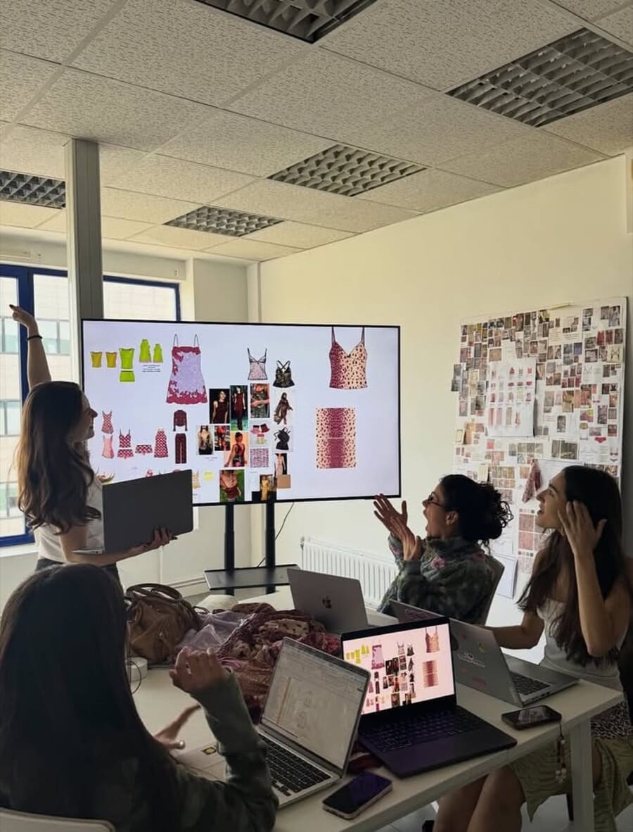 Team at a long table reviewing a moodboard on a large screen, with photos pinned on the wall