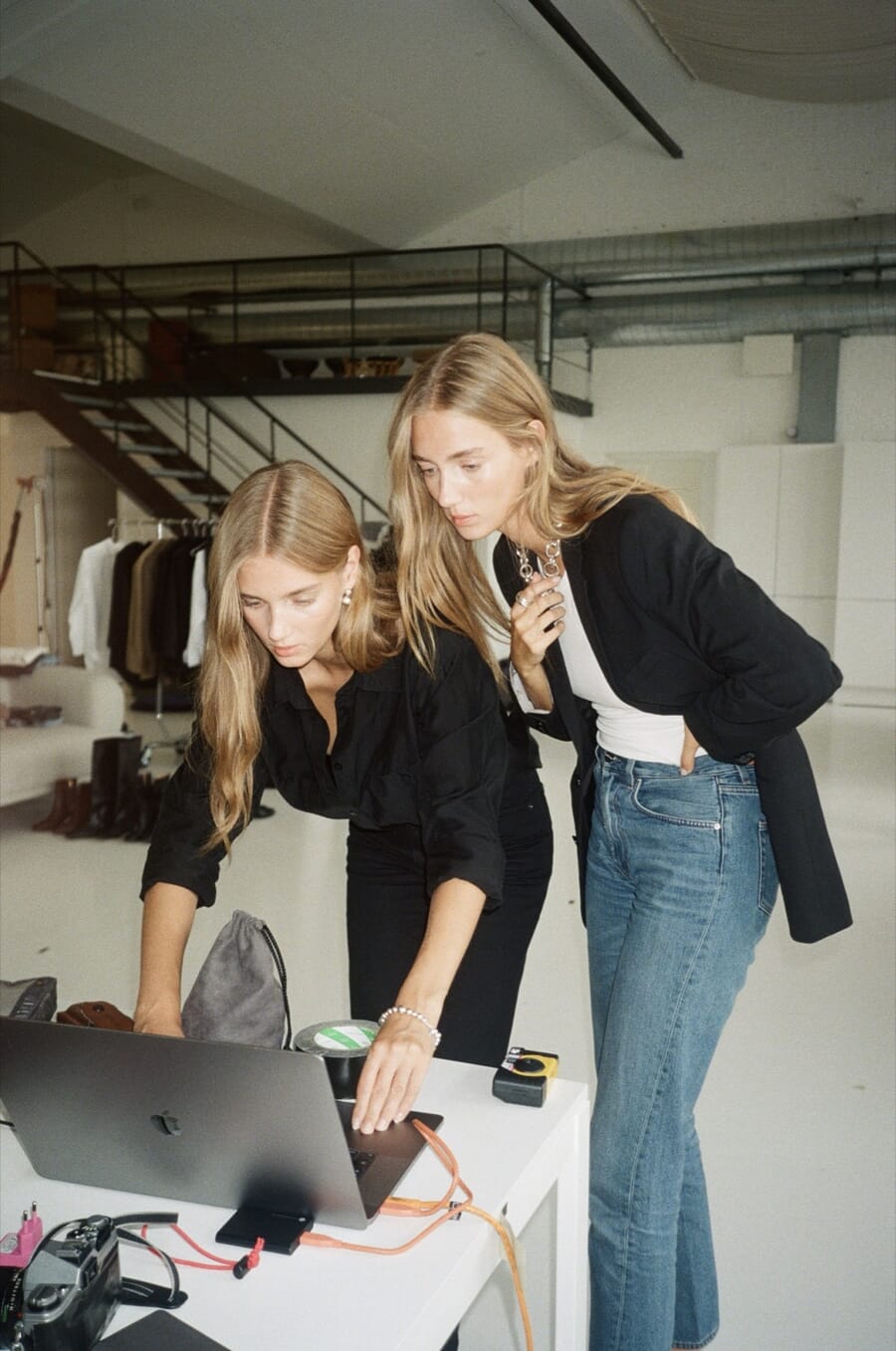 Two designers leaning over a laptop at a studio desk