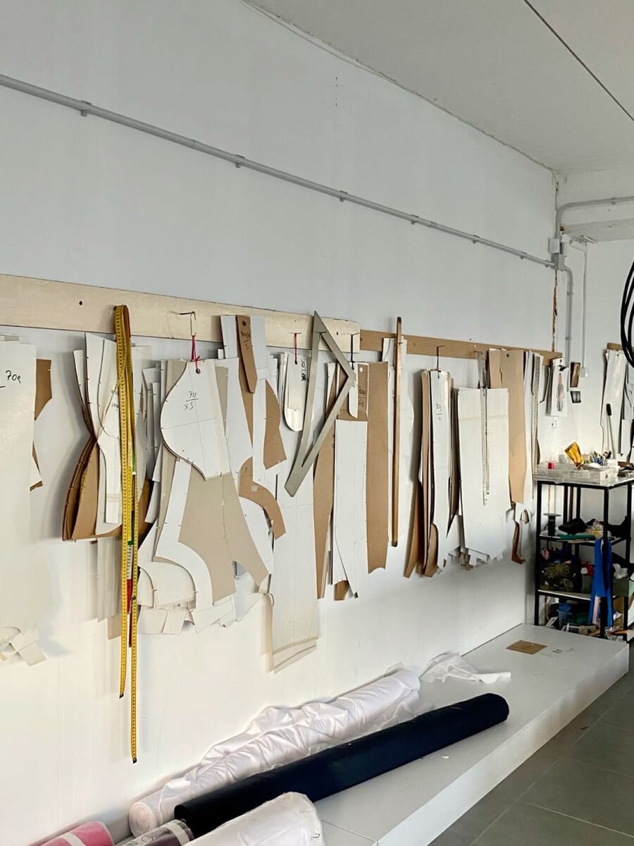 Paper pattern pieces hanging along a studio wall above a long cutting table