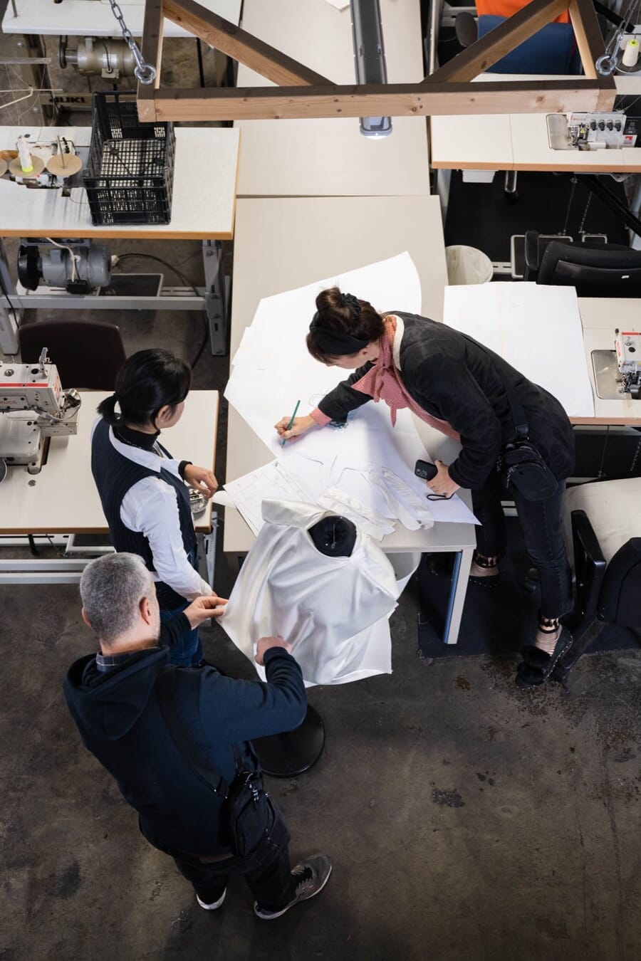 Overhead view of a team measuring and adjusting a garment on a cutting table
