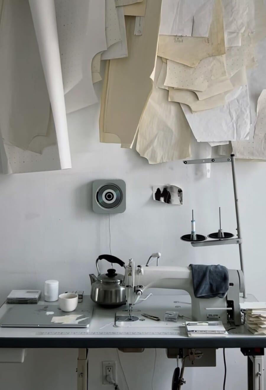 Sewing machine on a table with paper patterns pinned to the wall above it