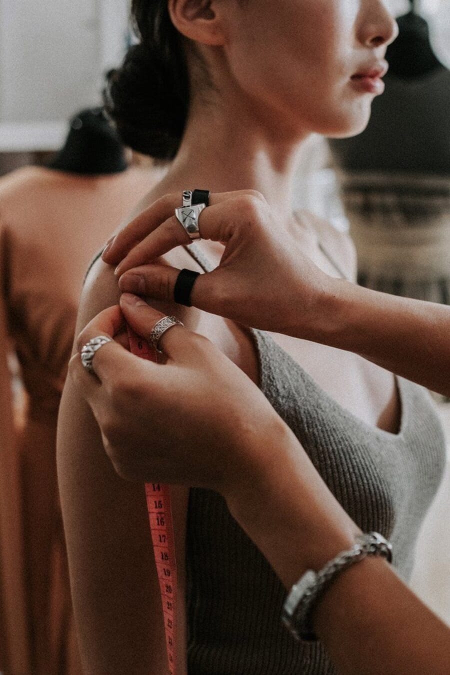 Hands measuring across the shoulder of a fitted top with a tape measure